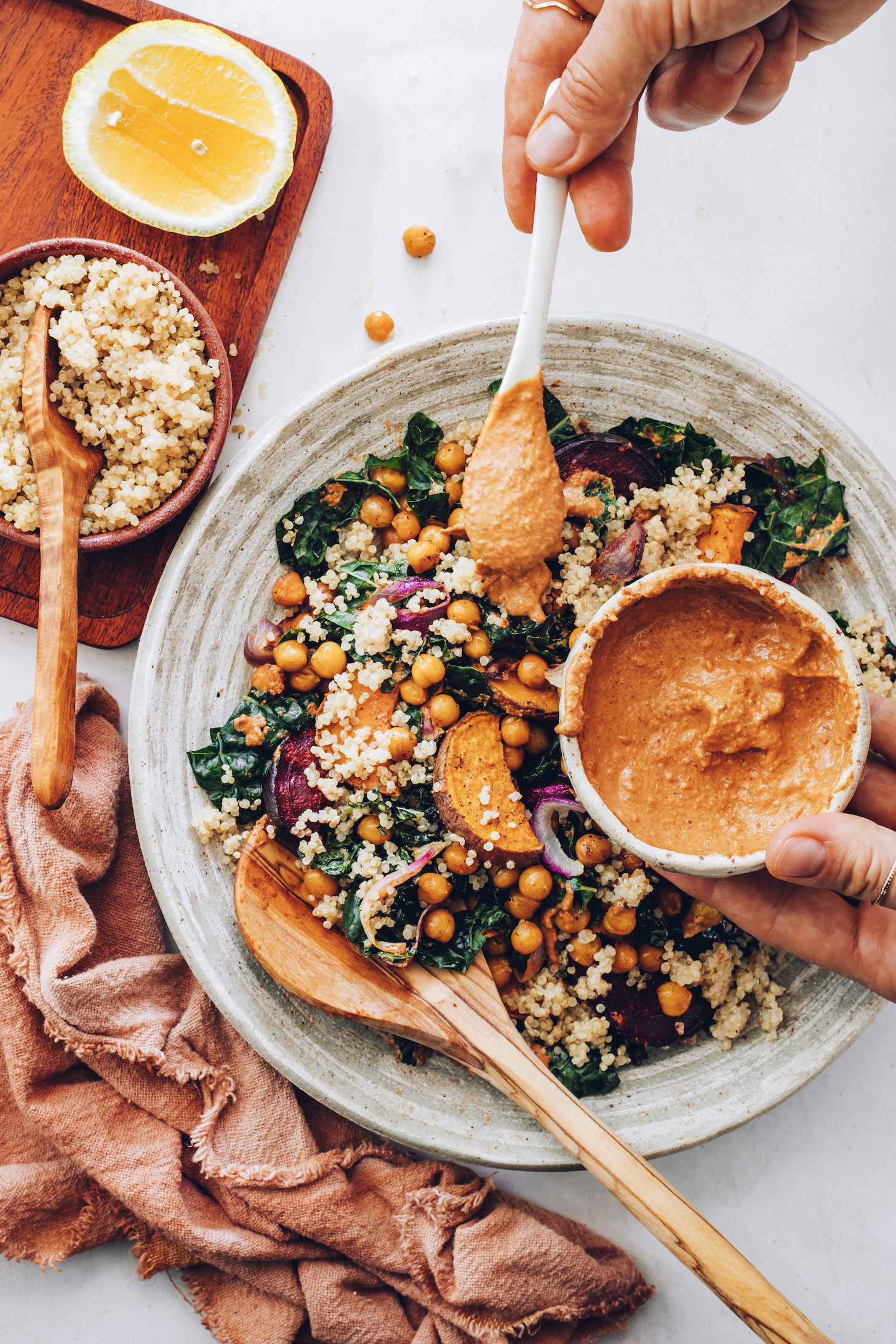 Scooping chipotle pecan pesto from a bowl onto a kale salad