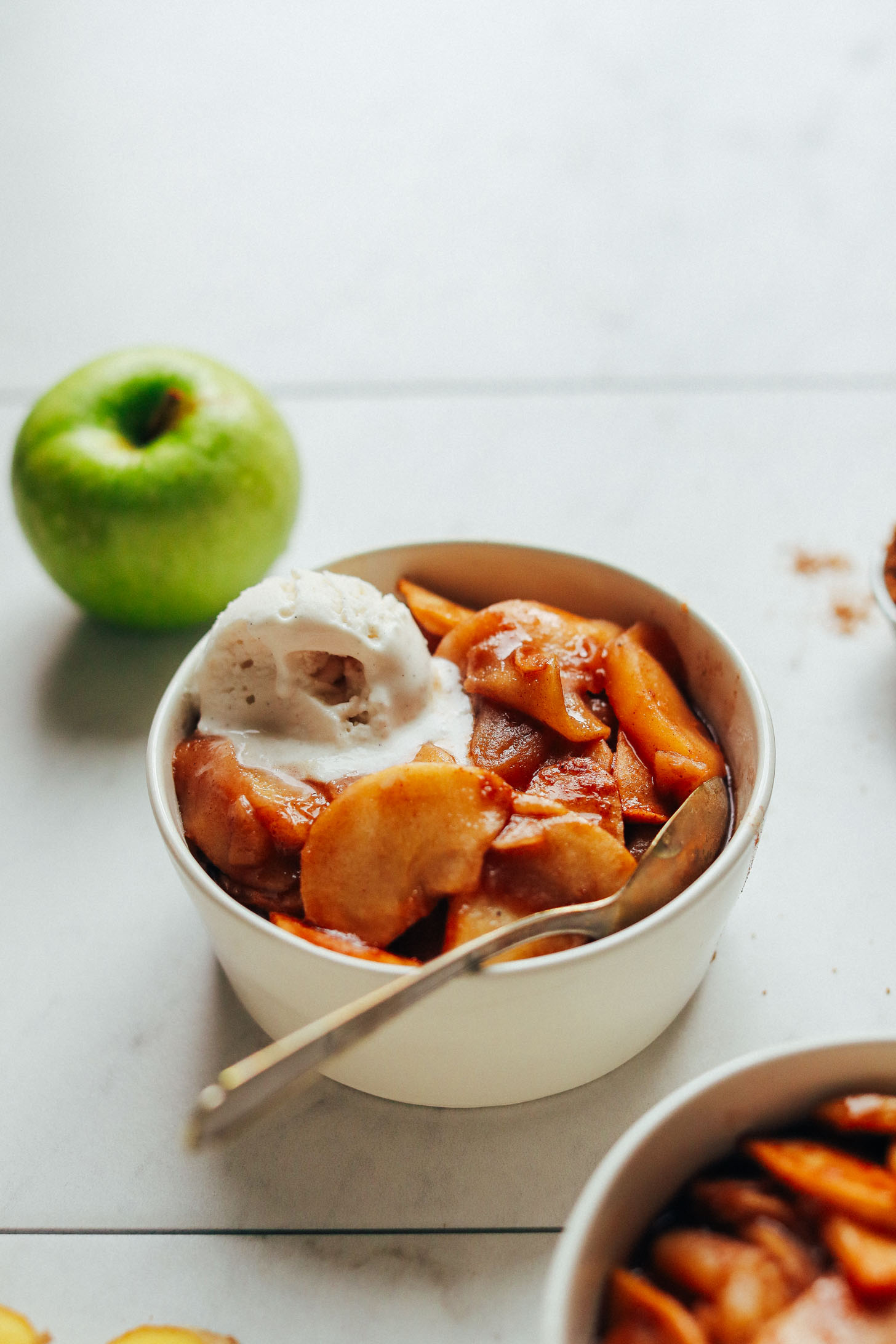 Close up shot of a bowl of our Cinnamon Baked Apples recipe topped with vegan ice cream