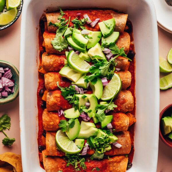 Ceramic casserole dish filled with vegan butternut squash black bean enchiladas