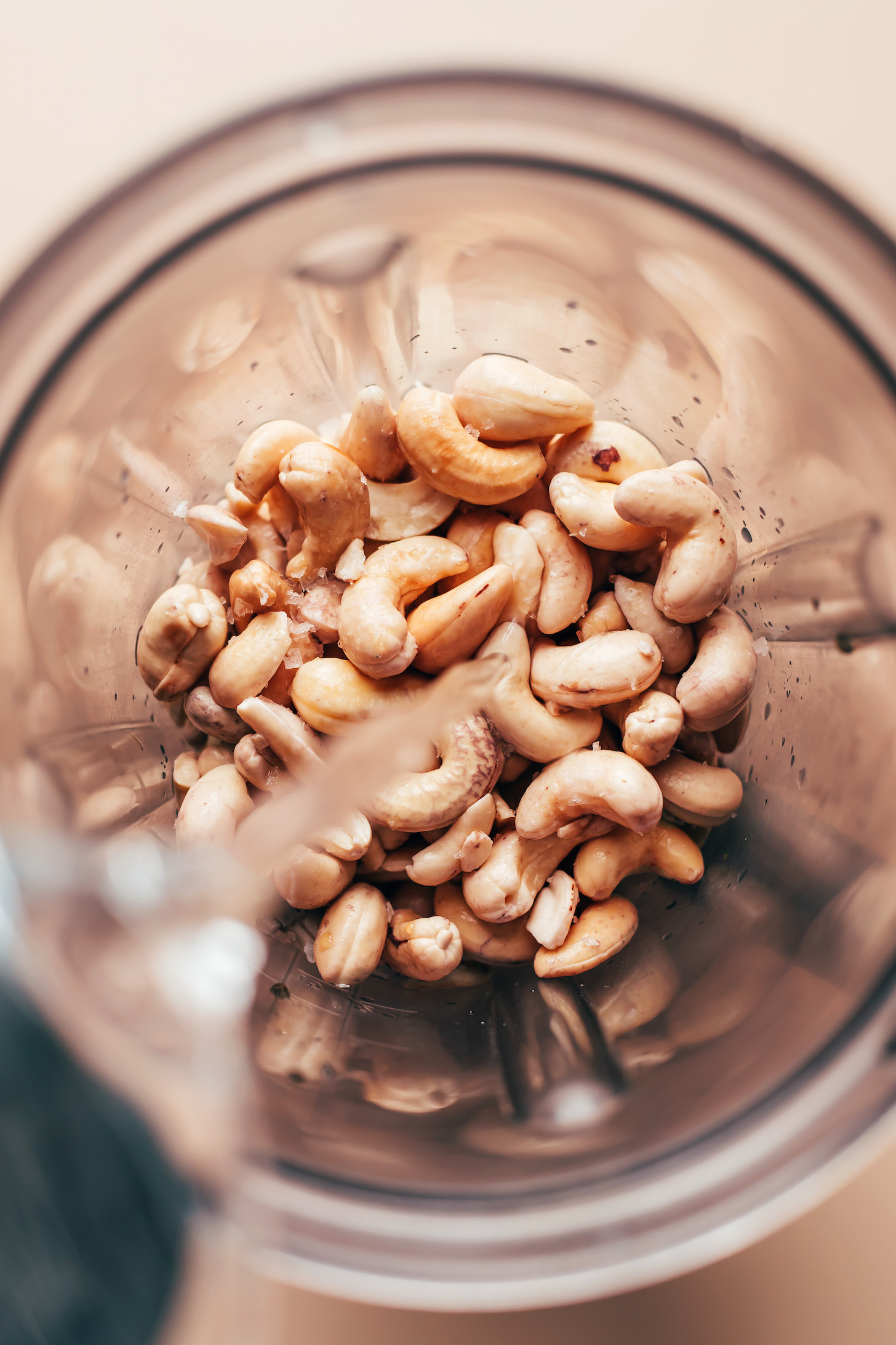 Pouring water over cashews in a blender