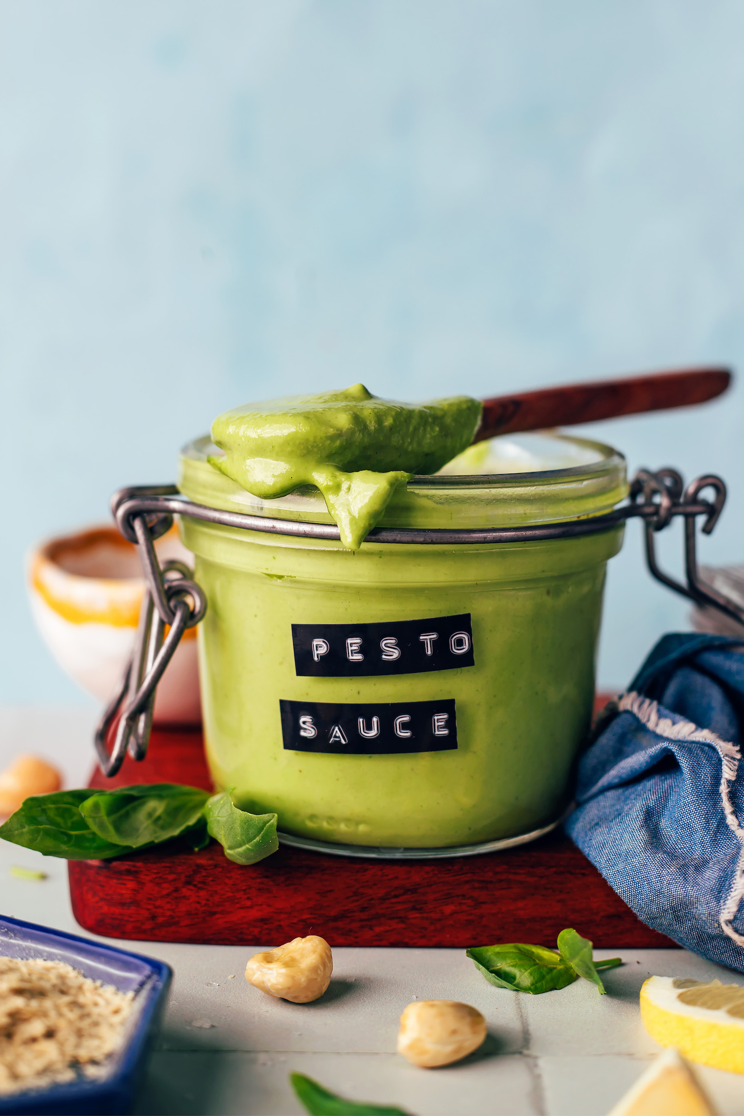 Spoonful of creamy pesto sauce resting on top of a jar with more sauce in it