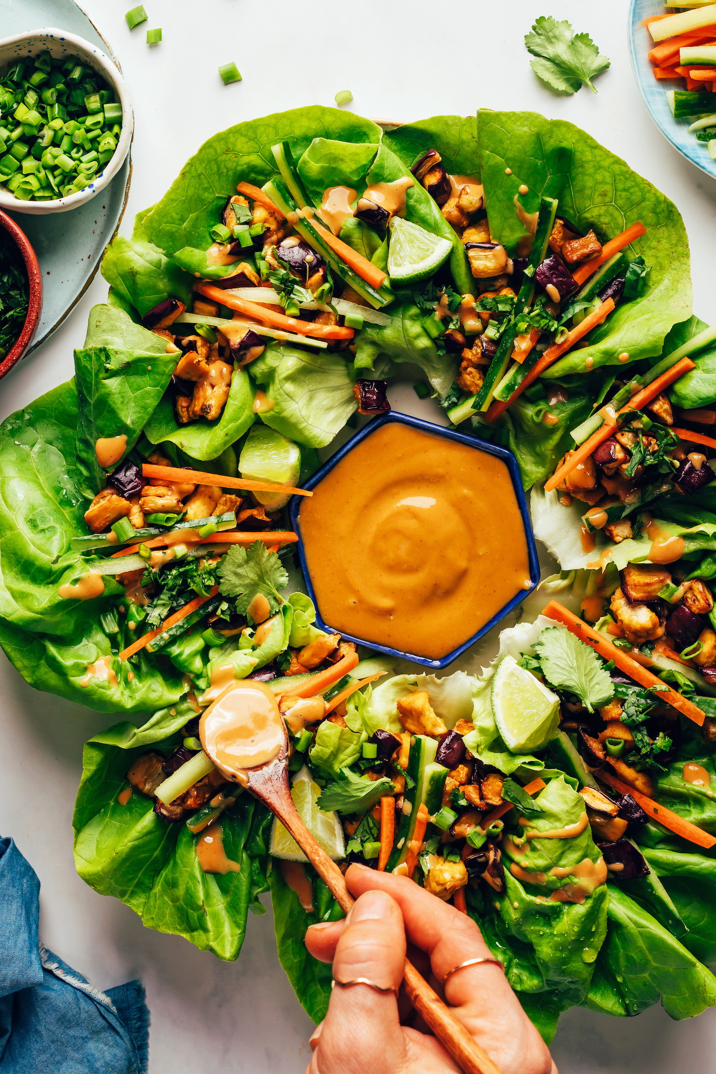 Drizzling a savory sesame sauce onto an eggplant tofu lettuce cup