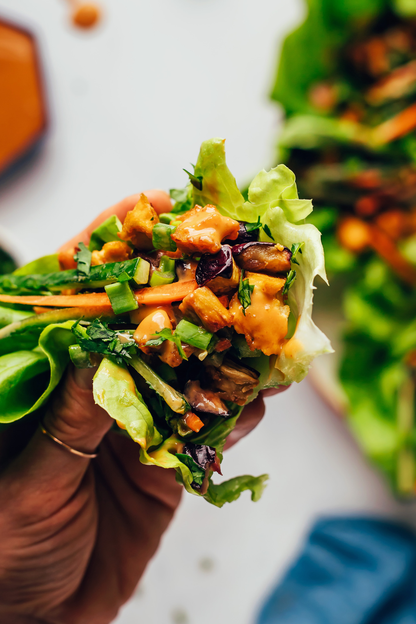 Holding up a tofu and eggplant lettuce cup filled with veggies and herbs