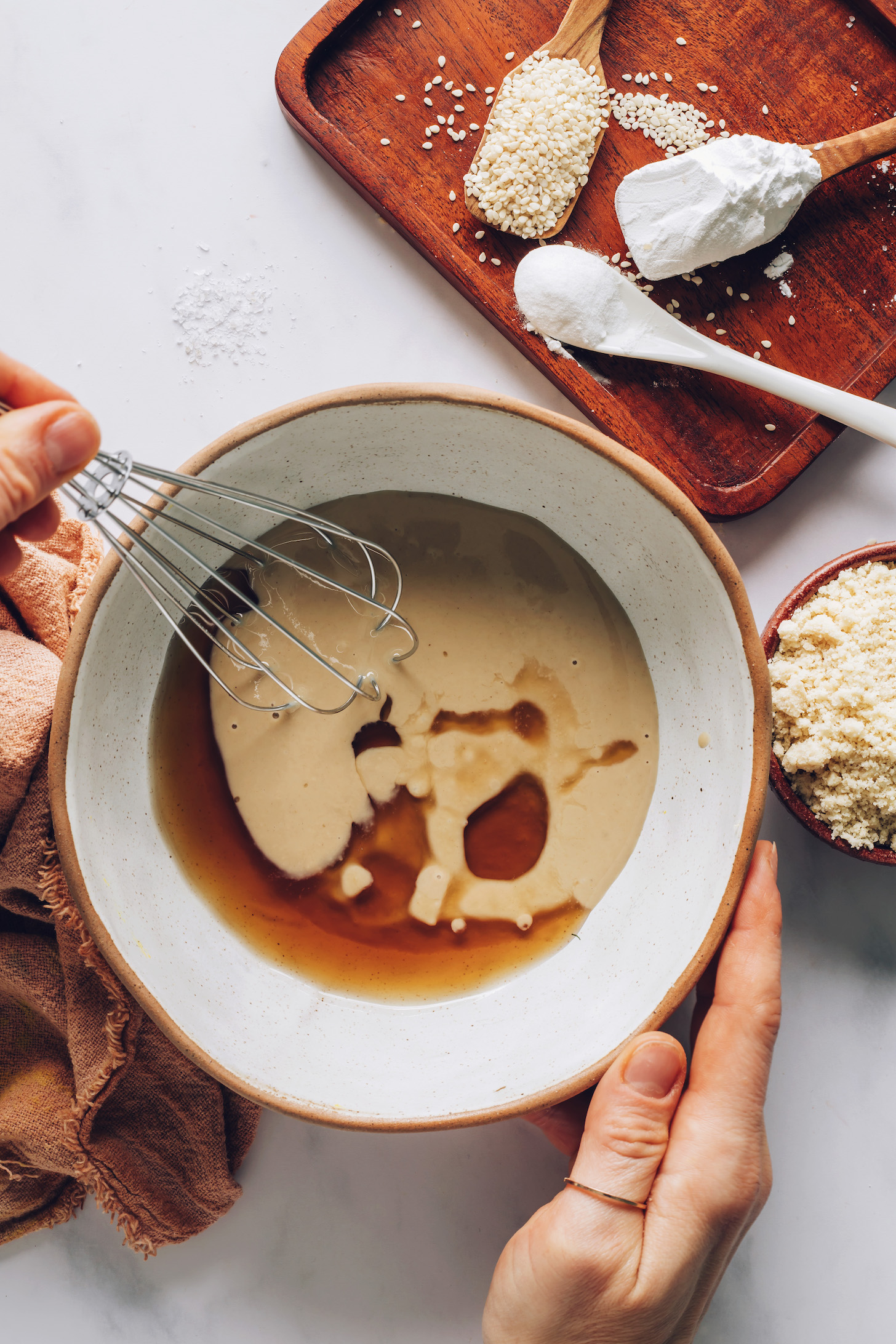 Using a whisk to combine tahini and maple syrup