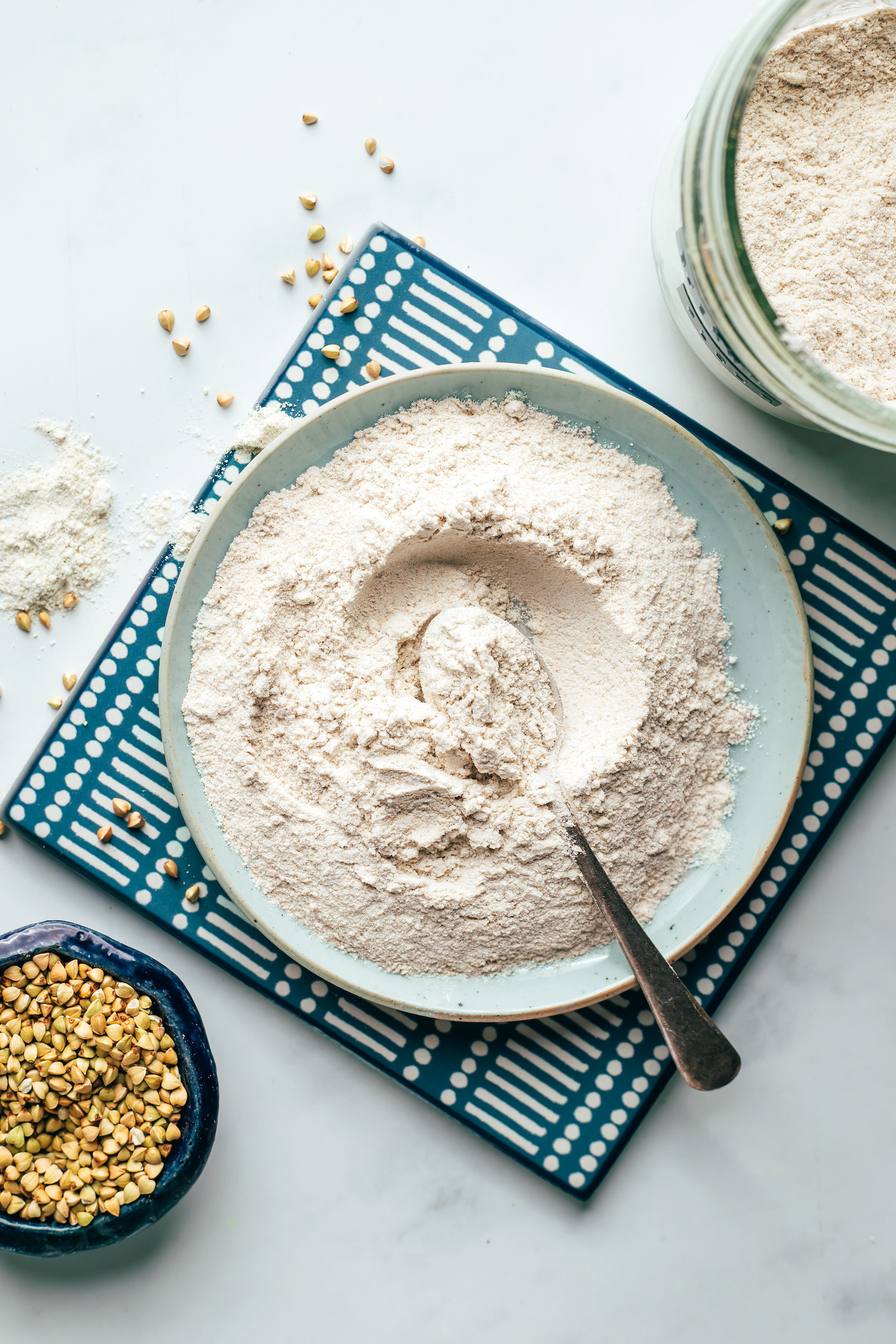 Bowl of homemade buckwheat flour next to a bowl of raw buckwheat groats