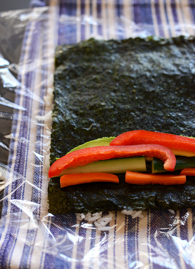 Inside Out Sushi Roll on a dish towel topped with plastic wrap