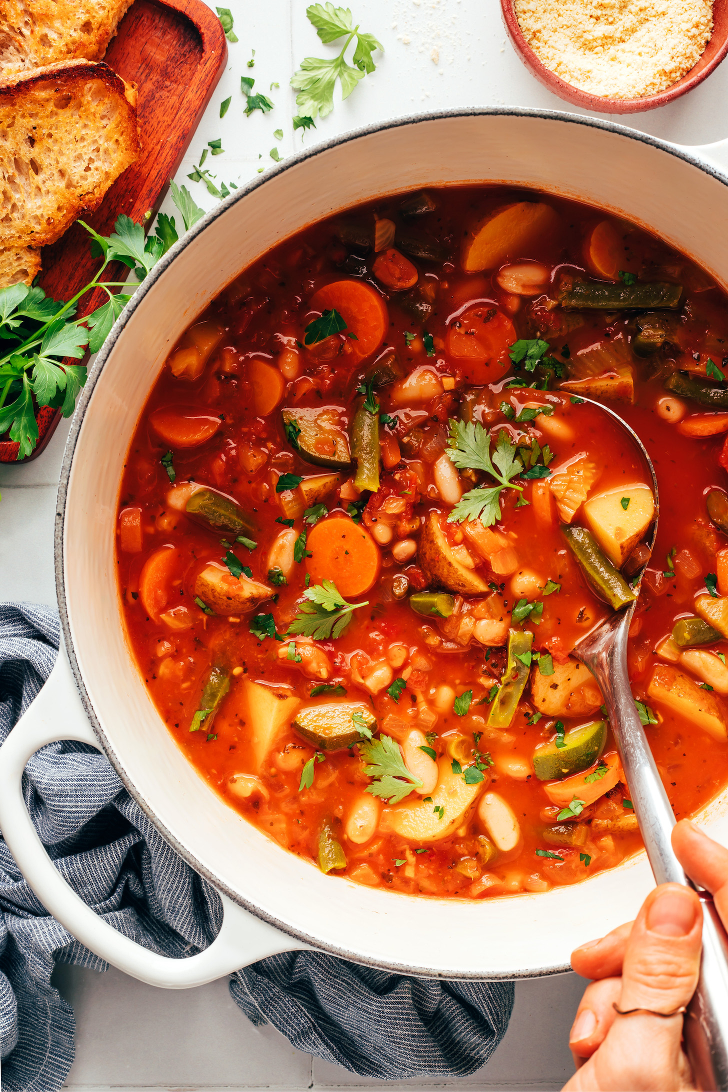 Holding a ladle in a pot of veggie white bean minestrone