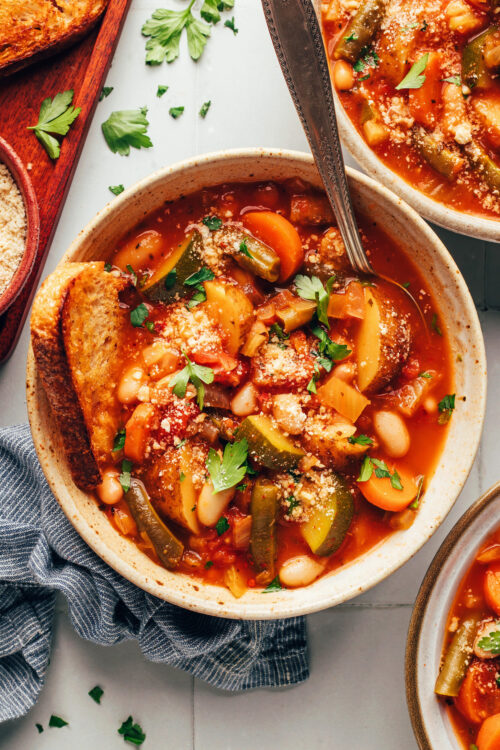 Bowl of white bean minestrone with a slice of bread in it