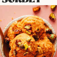 Overhead photo of a bowl with scoops of apricot sorbet topped with candied pecans