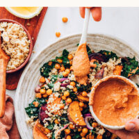 Bowl of hearty vegan and gluten-free kale salad with a bowl of chipotle pecan pesto beside it