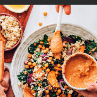 Bowl of hearty vegan and gluten-free kale salad with a bowl of chipotle pecan pesto beside it