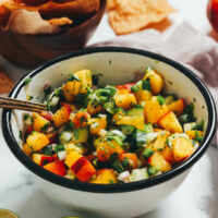 Tortilla chips next to a bowl of fresh peach cucumber salsa