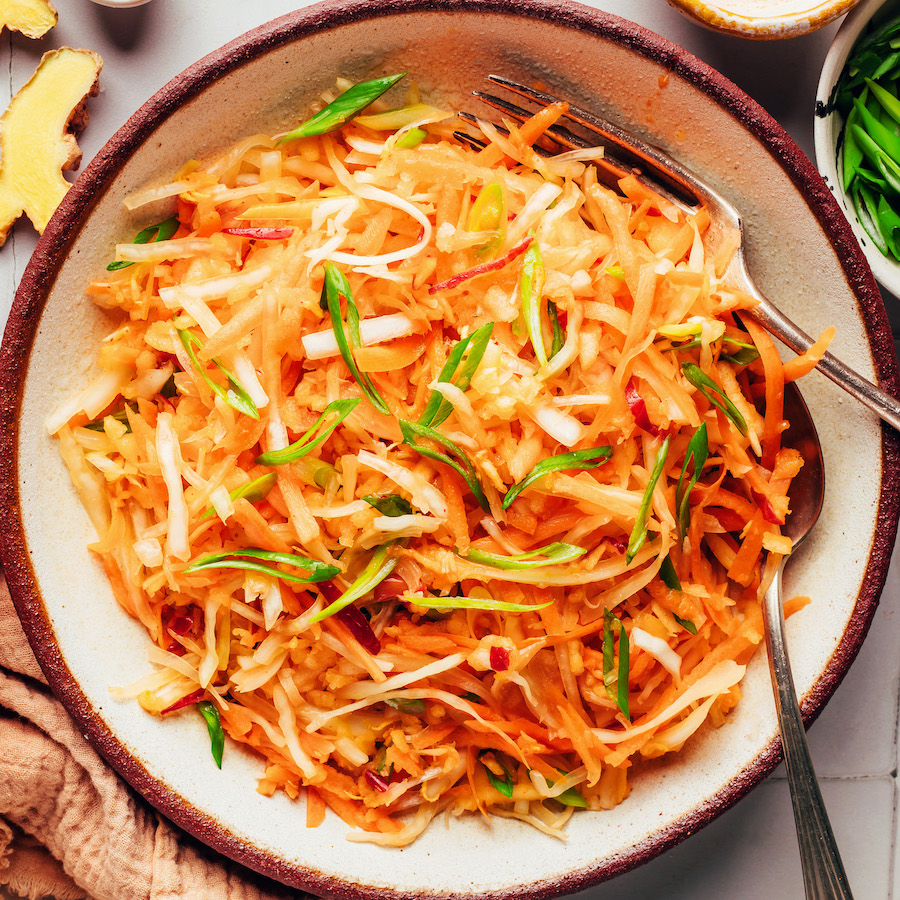 Serving spoon and fork in a bowl of Korean-inspired cabbage apple slaw