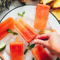 Hand picking up a tropical fruit popsicle made with whole fruit