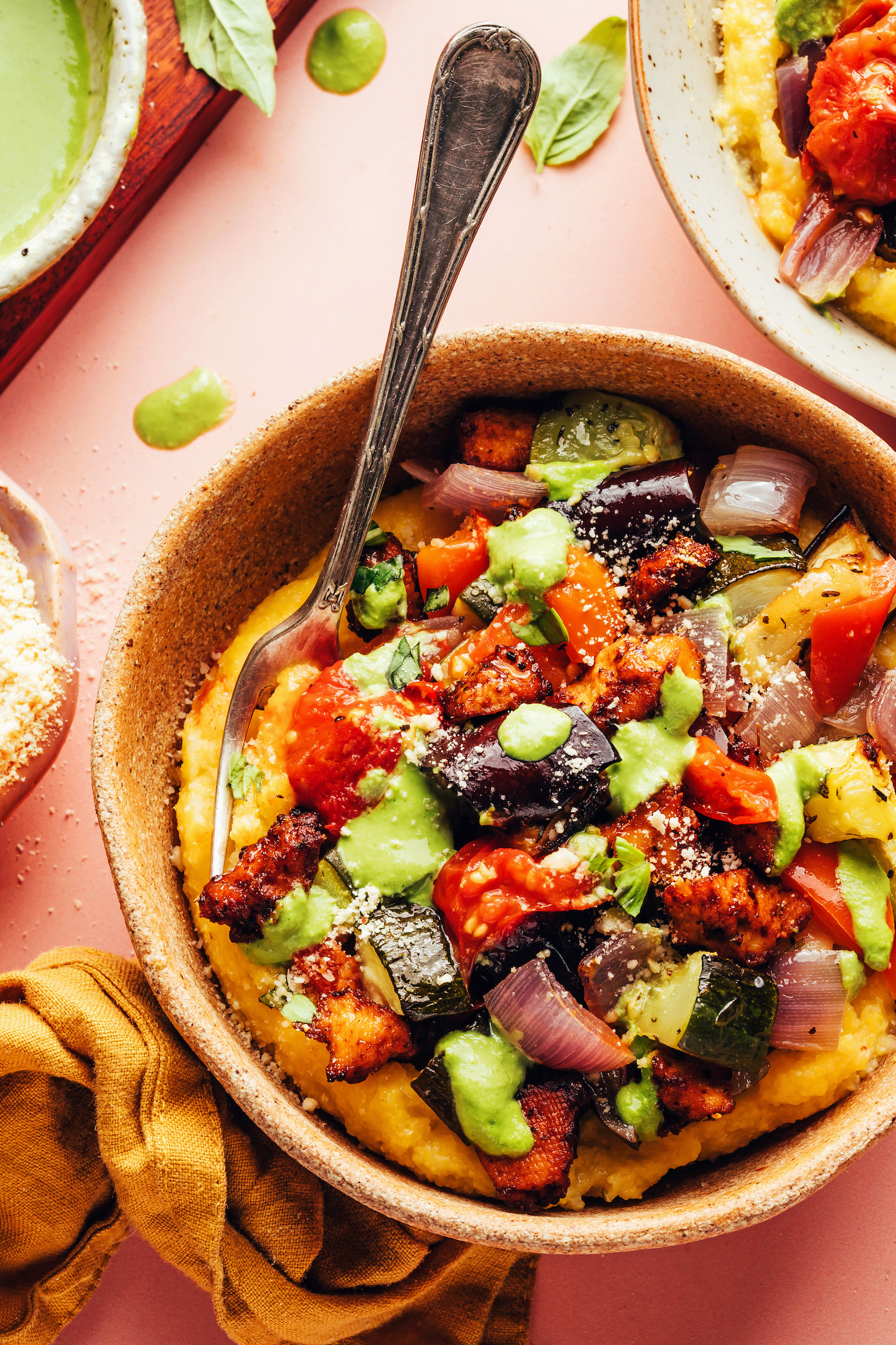 Bowl of our sheet pan ratatouille recipe with crispy baked tofu, polenta, and creamy pesto sauce