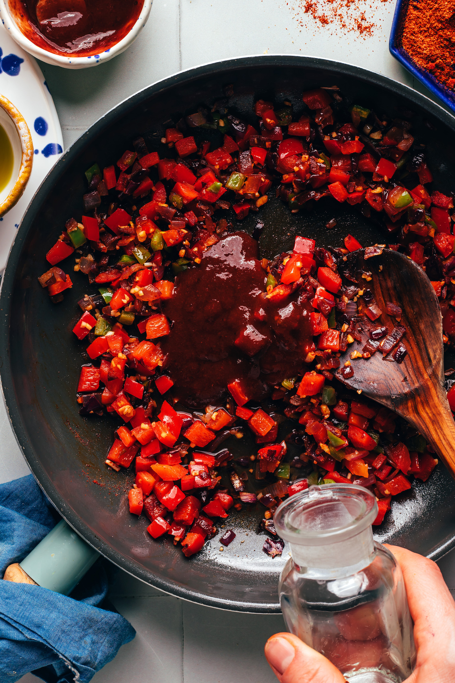 Drizzling water into a skillet of sautéed onions, peppers, and adobo sauce