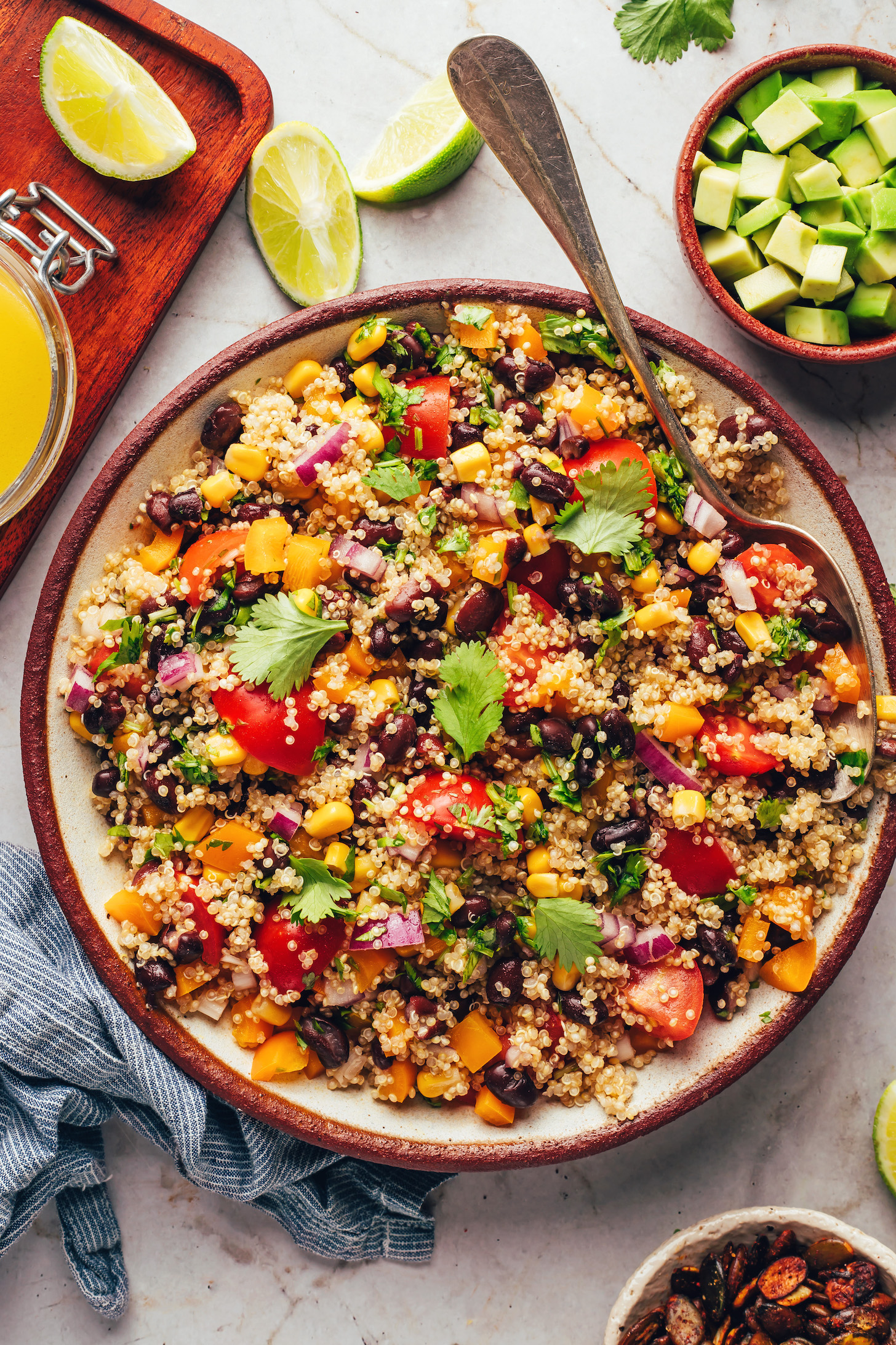 Avocado, lime wedges, and lime vinaigrette next to a bowl of our Southwest quinoa black bean salad