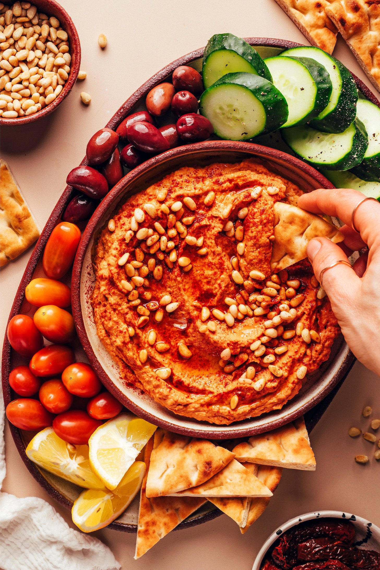 Dipping a slice of pita bread into a bowl of homemade sun-dried tomato hummus