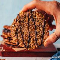 Holding up a florentine cookie decorated with a drizzle of dark chocolate