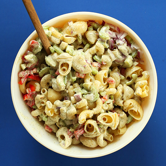 Wooden spoon in a bowl of Vegan Macaroni Salad